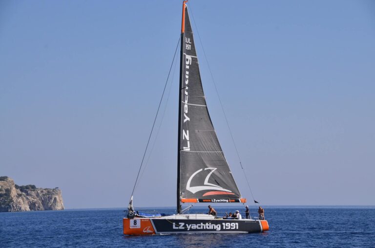 A sailboat glides smoothly over the deep blue sea under a cloudless sky, showcasing a perfect day for sailing.