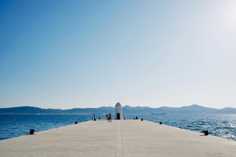 Explore the scenic view from the pier overlooking the ocean and distant mountains.